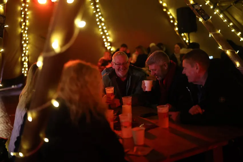 Friends enjoying the warm atmosphere beneath the lights inside a Christmas Town Tipi